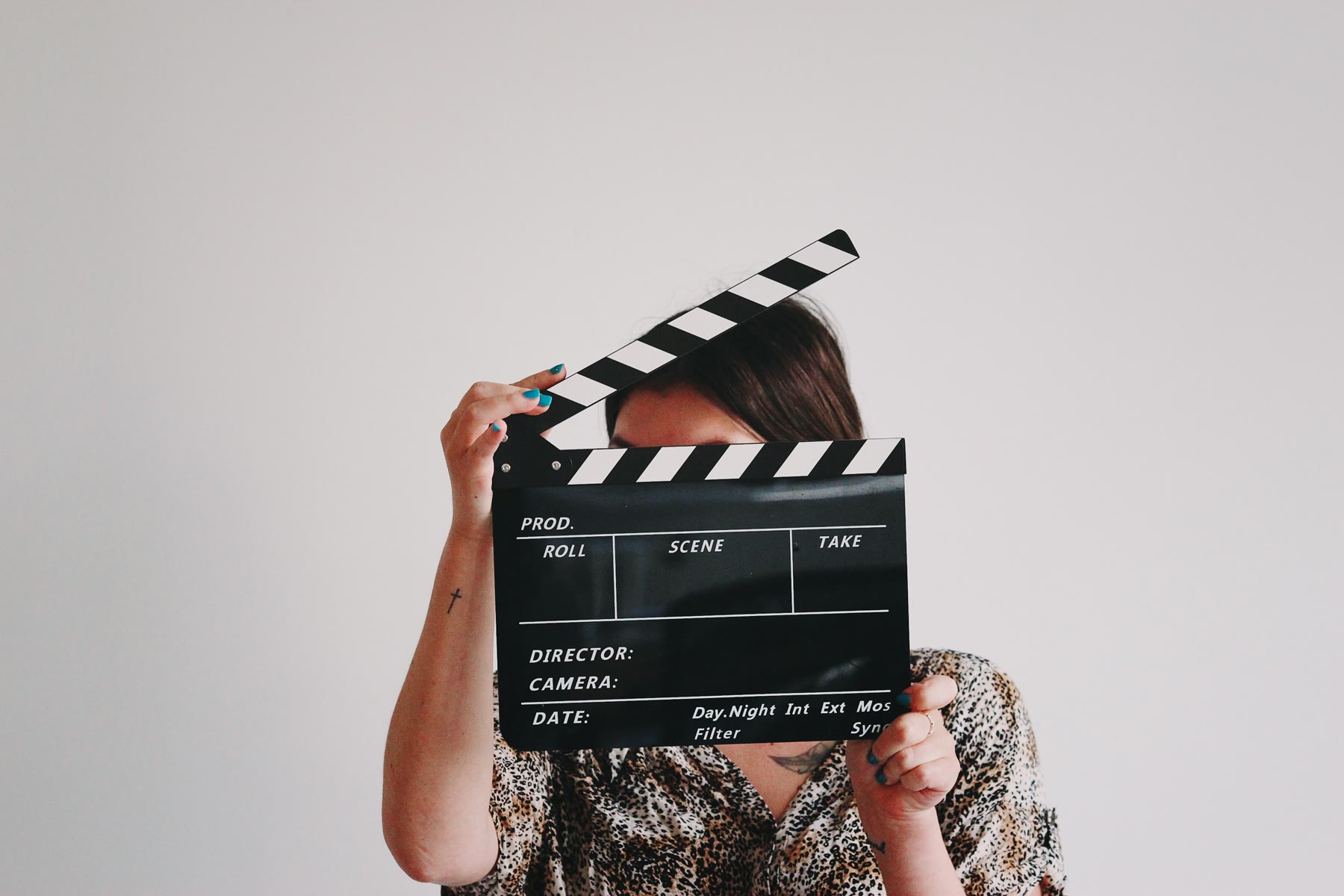 Ragazza che tiene un ciak cinematografico davanti al viso durante una ripresa
